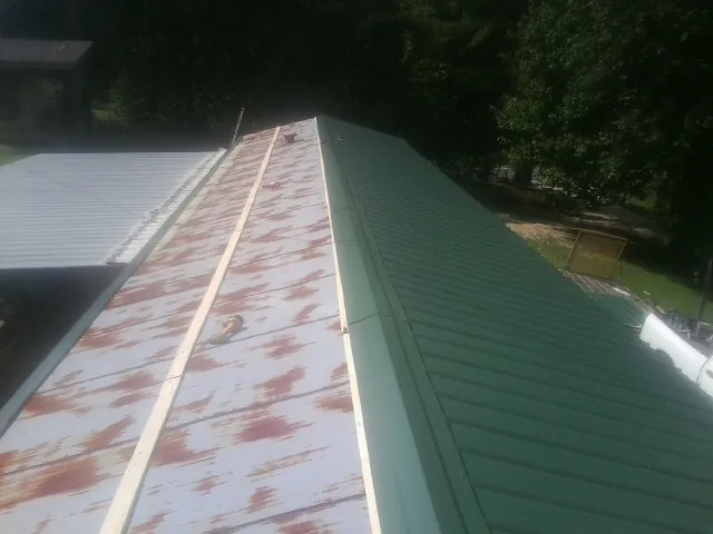 Old rusted panels beside newly installed green metal roofing — Wind Damage Roof Repair by Roofing Brothers in Mount Horeb