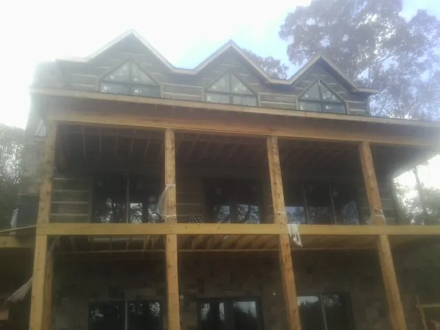Dormers and porch framing on a large log home under construction — Roof Coating work by our crew in Mount Horeb