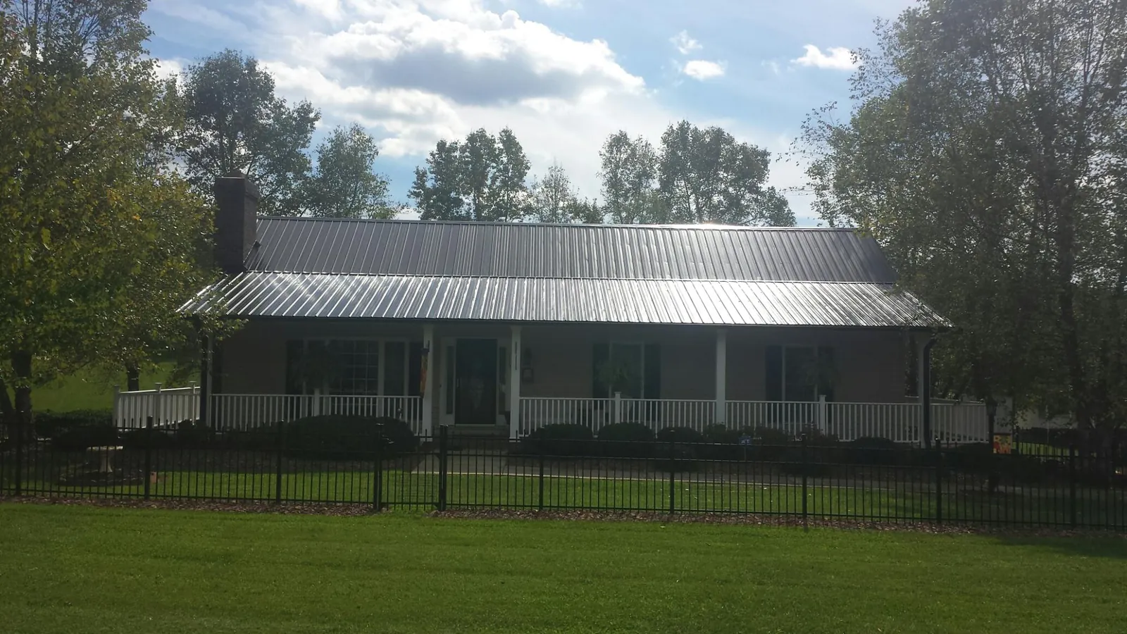 Gray metal roof on a brick ranch with a full width front porch — Gutter Guard Installation work by our crew in Mount Horeb