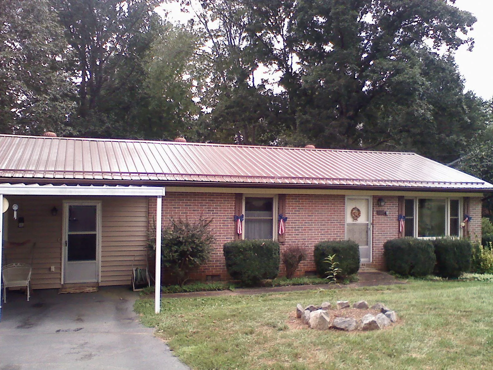 Bronze metal roof and carport on a brick ranch home — Roof Repair work by our crew in Mount Horeb