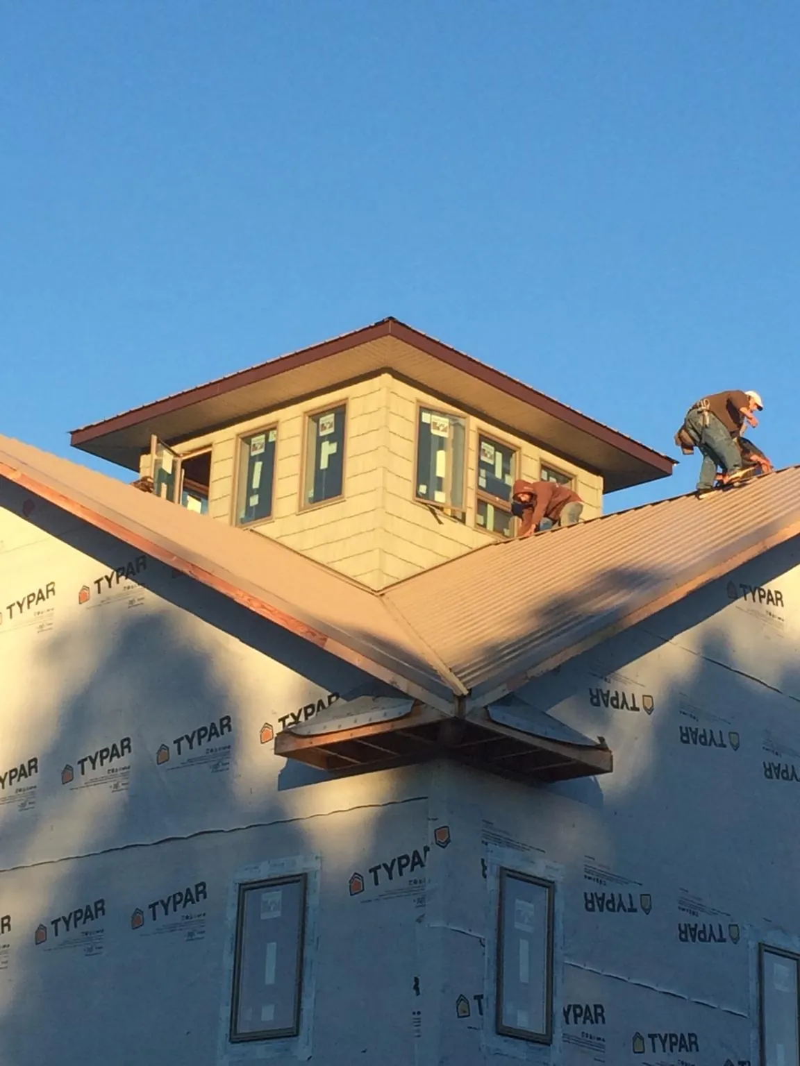 Roofers working around a rooftop cupola on a new metal roof at sunset — Roof Waterproofing in Mount Horeb by Roofing Brothers